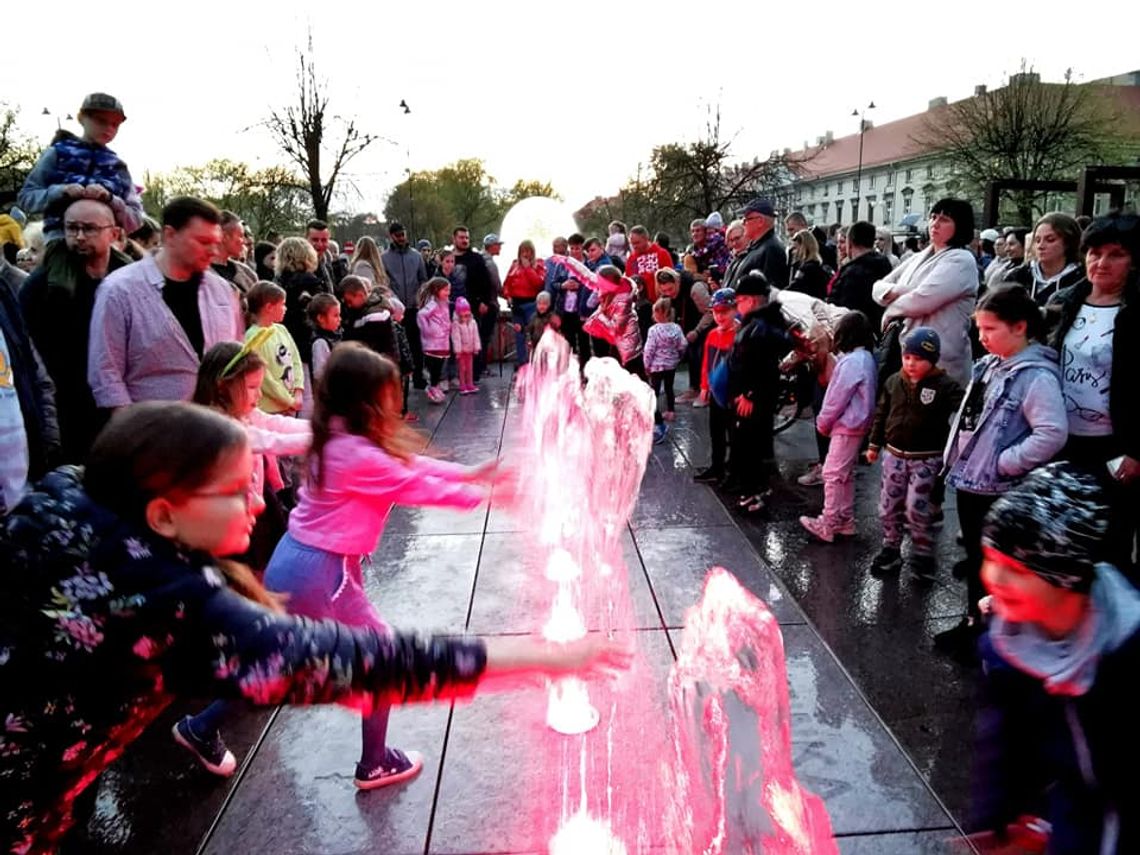 Tłumy w centrum miasta. Fontanna już tryska wodą i światłem