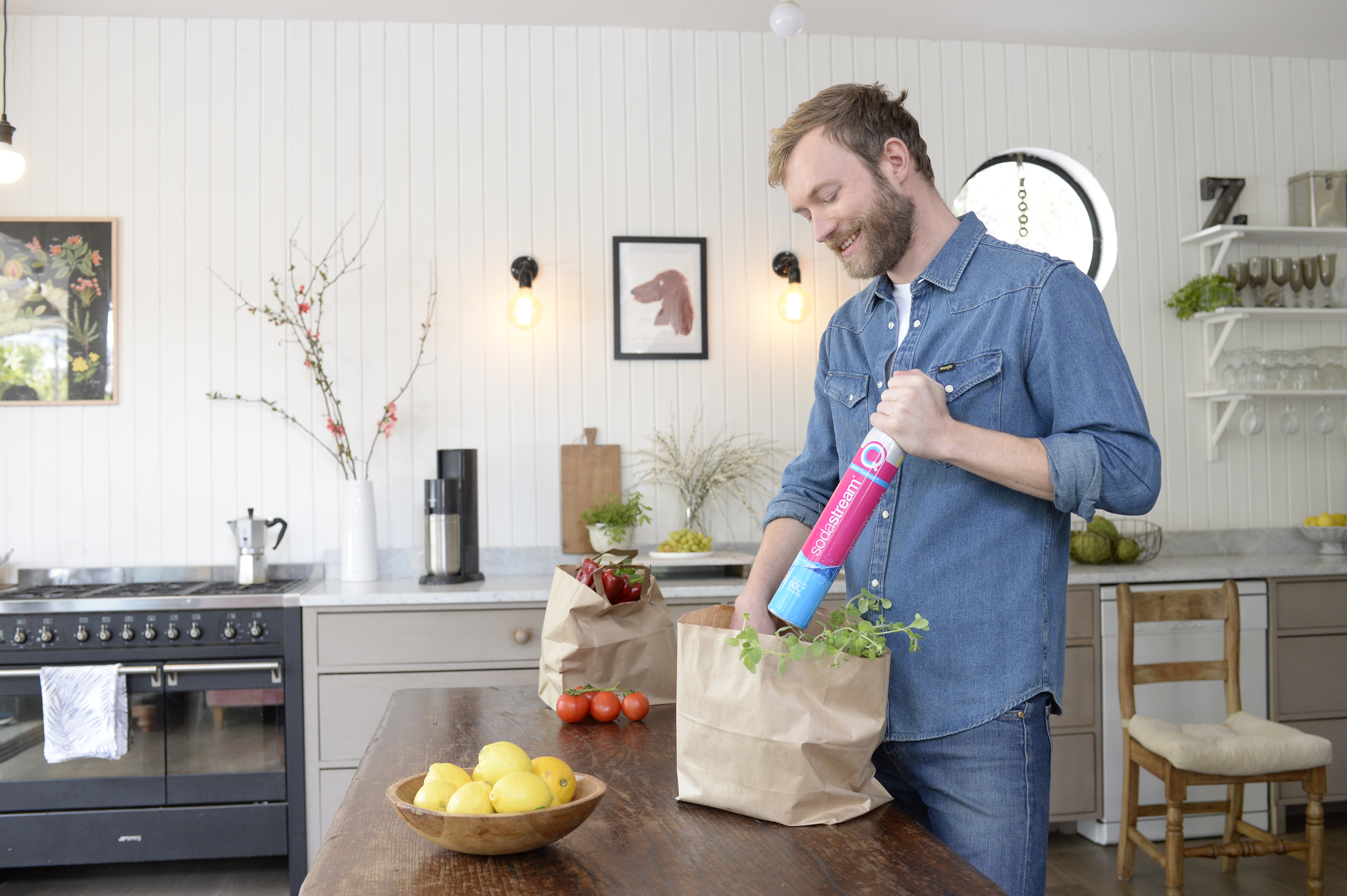 Mężczyzna wypakowuje z torby pełen cylinder CO2 SodaStream gotowy do wymiany w saturatorze.